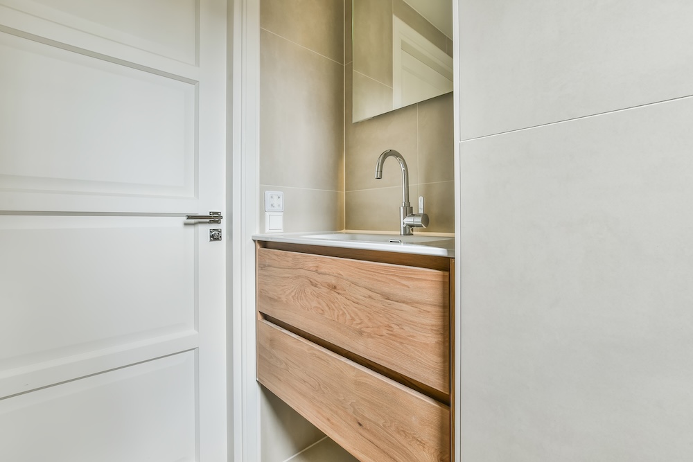 umywalka z szafką obok drzwi łazienkowych 